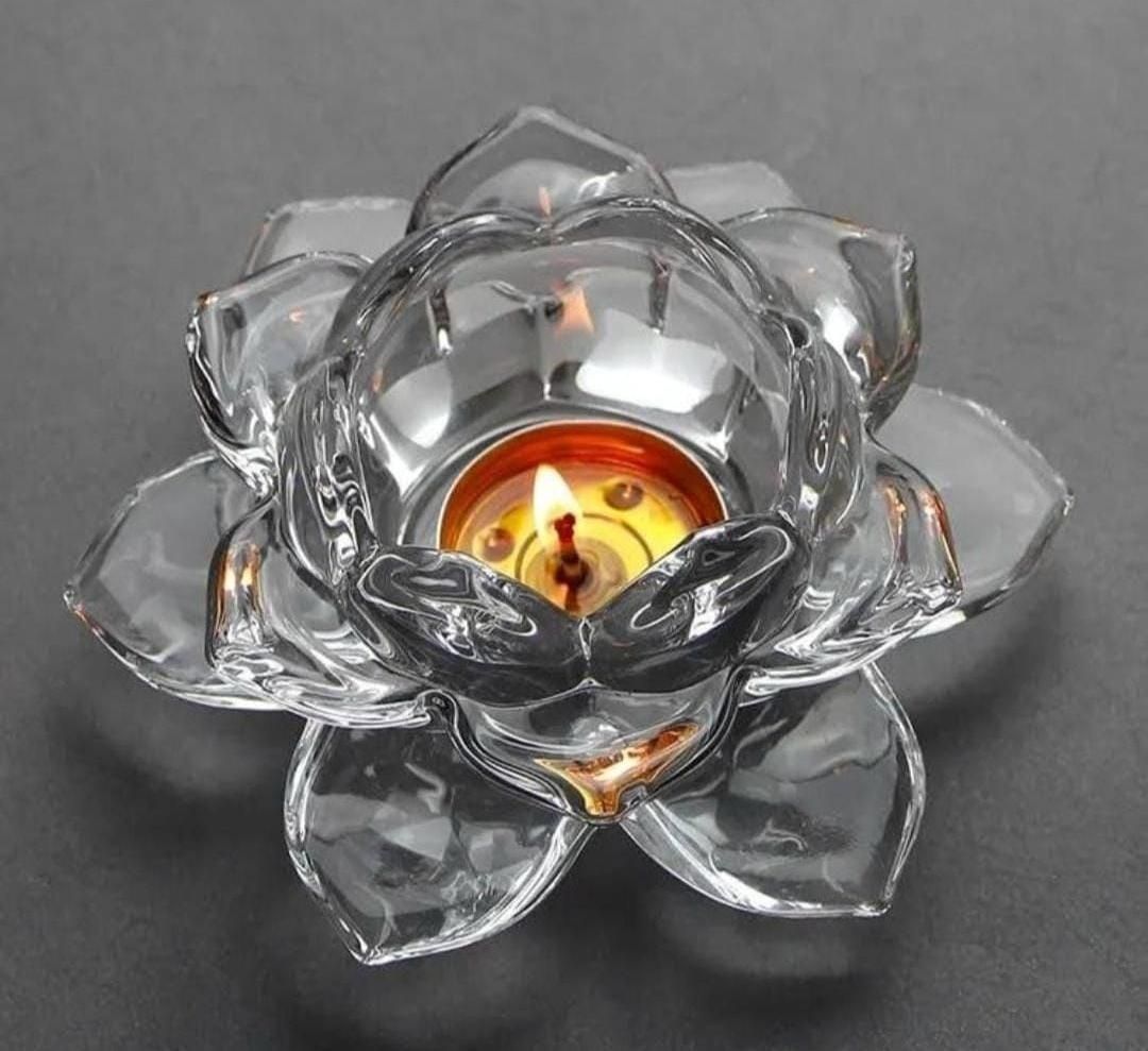 Glass lotus flower candle holder with a lit candle on a dark background